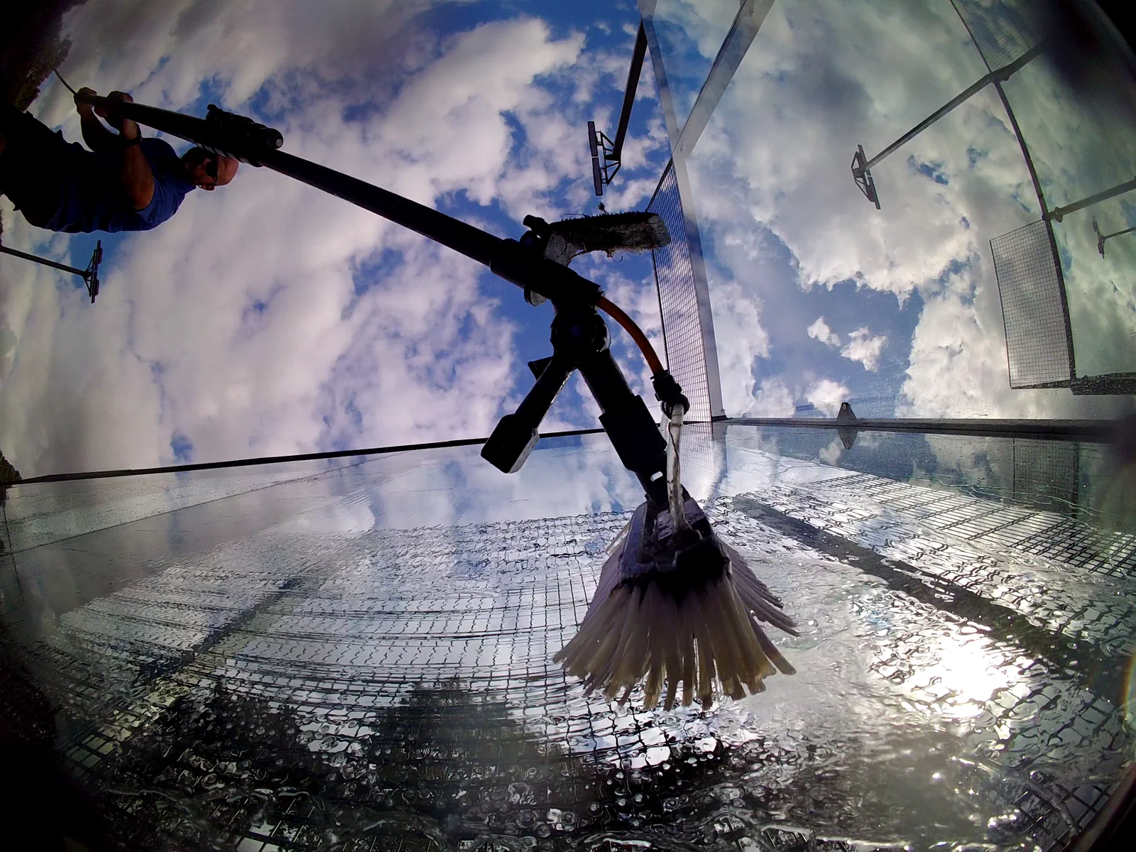 Close-up of a water-fed brush cleaning padel court glass